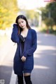 A woman in a blue cardigan is posing for a picture.