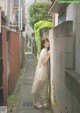 A woman leaning against a wall in an alleyway.