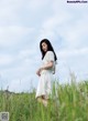 A woman in a white dress standing in tall grass.