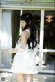 A woman in a white dress standing on a porch.