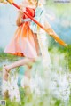 A woman in a dress holding a sword in a field.