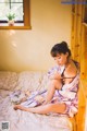 A woman in a kimono sitting on a bed.