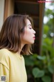 A woman in a yellow shirt is looking away from the camera.