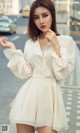 A woman in a white dress is posing for a picture.