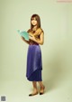 A woman in a purple pleated skirt holding a book.