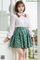 a woman in a white shirt and green skirt posing for a picture