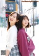 A couple of young women standing next to each other on a city street.