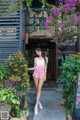 A woman standing in front of a building with flowers.