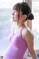 A woman in a pink leotard looking out a window.